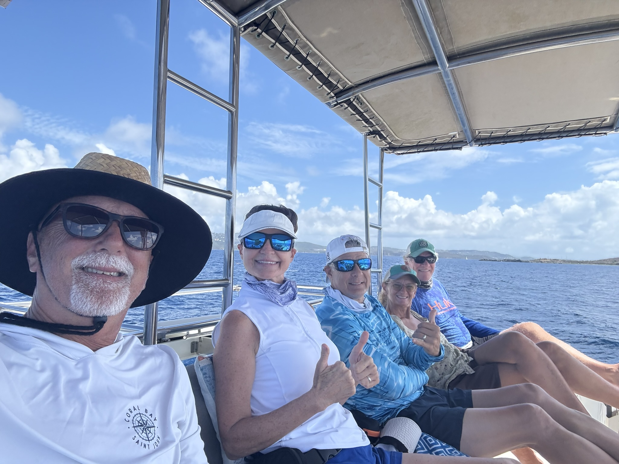 A group of smiling guests relaxing together under the shade aboard Great Adventure